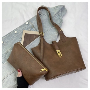 Flat lay of deep brown faux leather tote bag with matching zippered pouch on denim