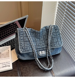 Close-up of quilted denim shoulder bag with silver turn-lock and metal chain strap
