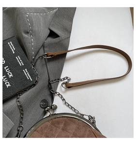 Close-up of brown quilted suede handbag with retro metal frame and chain strap