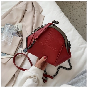 Detail of red vintage shell bag showing metal clasp closure and fine cross-stitch texture