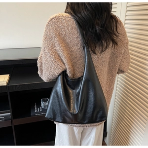 Detail showing the glossy black leather texture and vertical stitching on the shoulder bag