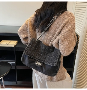 Detail of black denim quilted shoulder bag with silver chain strap and metal clasp