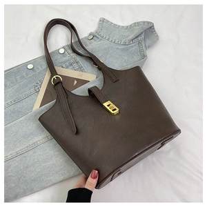 Detail of dark brown leather tote bag with gold metal twist lock and adjustable strap