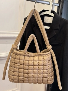 Sac fourre-tout matelassé beige chic avec bandoulière à nœud sur un cintre minimaliste