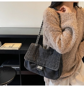Detail of grey washed denim shoulder bag with quilted pattern and metal chain strap