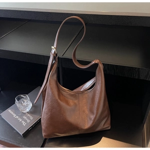Detail of dark brown hobo bag with oil-wax leather texture and adjustable metal buckle