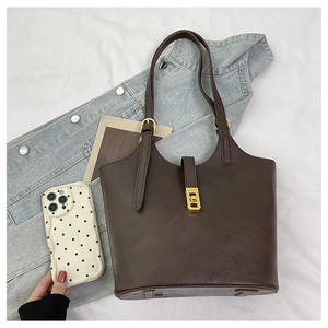 Close-up of dark brown tote bag featuring fine leather texture and gold metal buckle