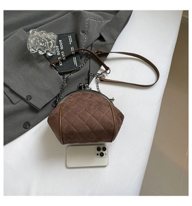 Macro shot of retro quilted suede shell bag with vintage metal clasp and chain strap