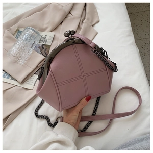 Detail of a vintage pink shell bag with cross-stitch pattern and metal bead clasp
