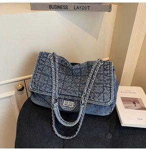Detailed close-up of quilted denim texture with silver metal chain and twist lock