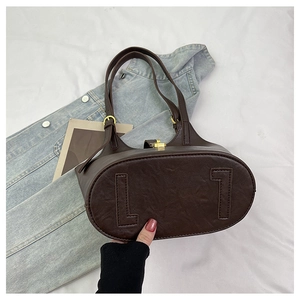 Detail of deep brown tote bag featuring unique L-shaped stitching and metal turn-lock closure