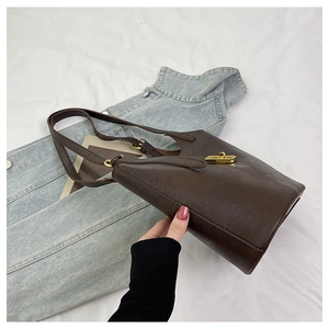 Detail view of a vintage dark brown leather bucket bag with gold twist lock and strap