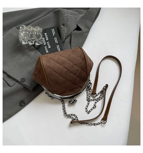 Close-up of brown quilted suede texture and vintage kiss-lock clasp on crossbody bag