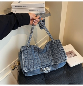 Detail of blue denim quilted handbag with silver chain strap and metal swivel lock