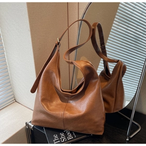 Detail of vintage brown large capacity tote bag with soft leather texture and golden buckle