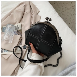 Detail of black pebbled leather kiss-lock bag with contrast white cross stitching
