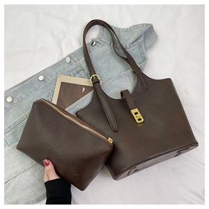 Detail view of deep brown leather tote set with matching clutch and golden buckle