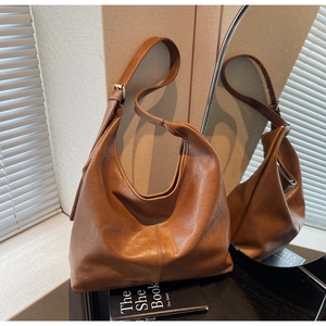 Detail of caramel leather hobo bag with adjustable strap and gold metal buckles