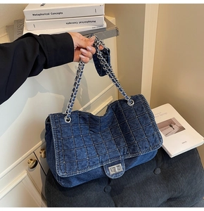 Detail of blue quilted denim bag featuring silver metal chain and twist lock buckle