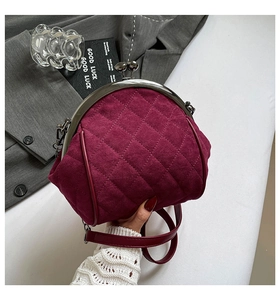 Detailed close-up of burgundy quilted velvet crossbody bag with vintage metal kiss-lock clasp