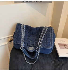 Detail of dark blue denim quilted bag with silver chain strap and metal turn-lock