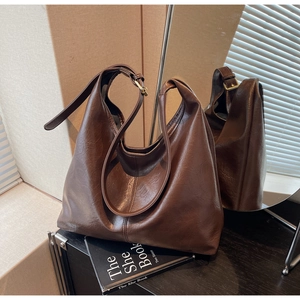 Detail of coffee brown faux leather tote with soft texture and golden metal hardware
