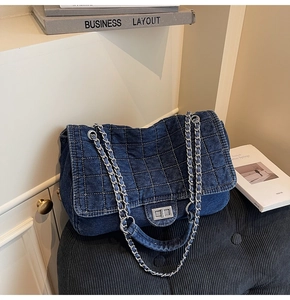 Detail of blue denim quilted handbag with silver chain strap and metal turn-lock closure