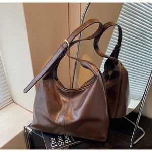 Detail of dark brown leather tote featuring soft texture and adjustable wide shoulder strap