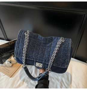 Detail of blue denim shoulder bag with silver turn-lock and quilted grid texture