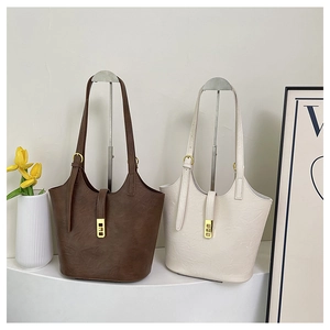 Detail view of large tote bags in brown and beige PU leather with gold metal buckles