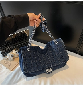 Detail of dark blue quilted denim shoulder bag with silver chain and metal turn-lock