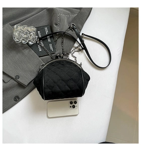 Detail view of quilted black chain bag with metal clasp and phone for size reference