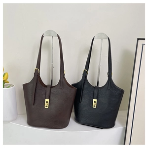 Detail view of large tote bags in black and brown leather with golden metal buckles