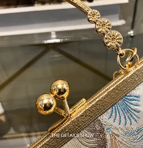 Detail of vintage embroidery and gold floral clasp on elegant Chinese style handbag