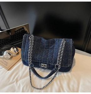 Detailed view of dark blue denim quilted bag with silver chain strap and metal clasp