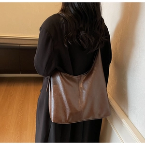 Rear view of a model wearing the brown large capacity hobo shoulder bag in faux leather