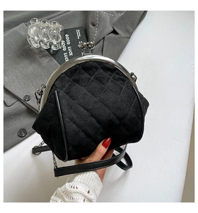 Detail of black quilted suede kiss-lock bag with vintage silver metal frame and chain