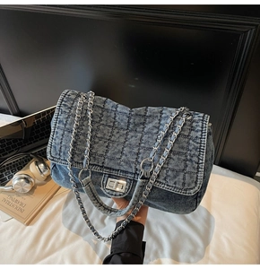 Detailed close-up of blue washed denim texture and silver chain strap on fashion bag