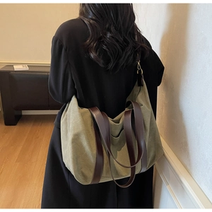 Rear view of model carrying army green canvas tote with brown leather straps for work
