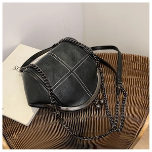 Detail of black shell bag with white cross stitching and metal frame kiss-lock closure