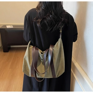 Close-up of olive green canvas tote bag featuring premium brown leather straps and metal hooks