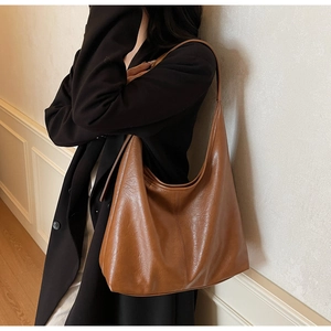 Close-up of caramel leather tote bag with soft texture and glossy finish shown on model