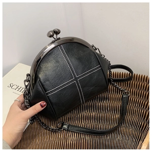 Detail of black PU shell bag featuring white cross stitching and metal frame clasp closure