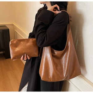 Detail of a brown faux leather tote bag set including a large shoulder bag and matching pouch