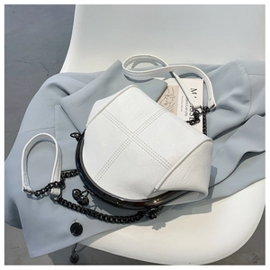 Close-up of white shell crossbody bag featuring metal frame and textured stitch detail