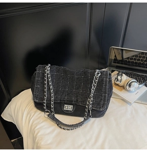 Detail view of dark grey quilted denim shoulder bag with silver chain and twist-lock clasp