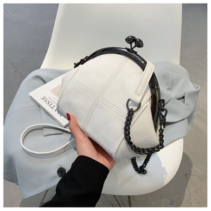 Detail of white leather shell bag featuring black metal clasp and chain strap on a chair