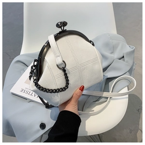 Detail of white quilted shell bag with black metal kiss-lock closure and dual straps