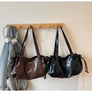 Vue détaillée de grands sacs cabas en similicuir marron foncé et noir avec cordons de serrage