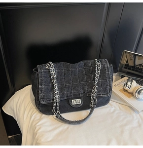 Close-up of black denim crossbody bag with silver chain and quilted diamond stitching